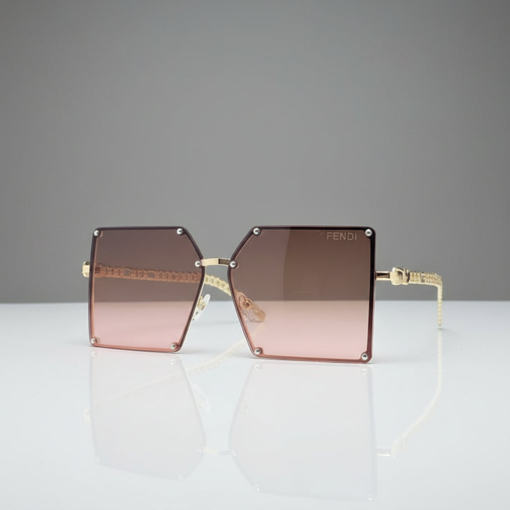 A pair of oversized square sunglasses with a gold-tone metal frame and gradient pink lenses, resting on a reflective white surface against a white background.